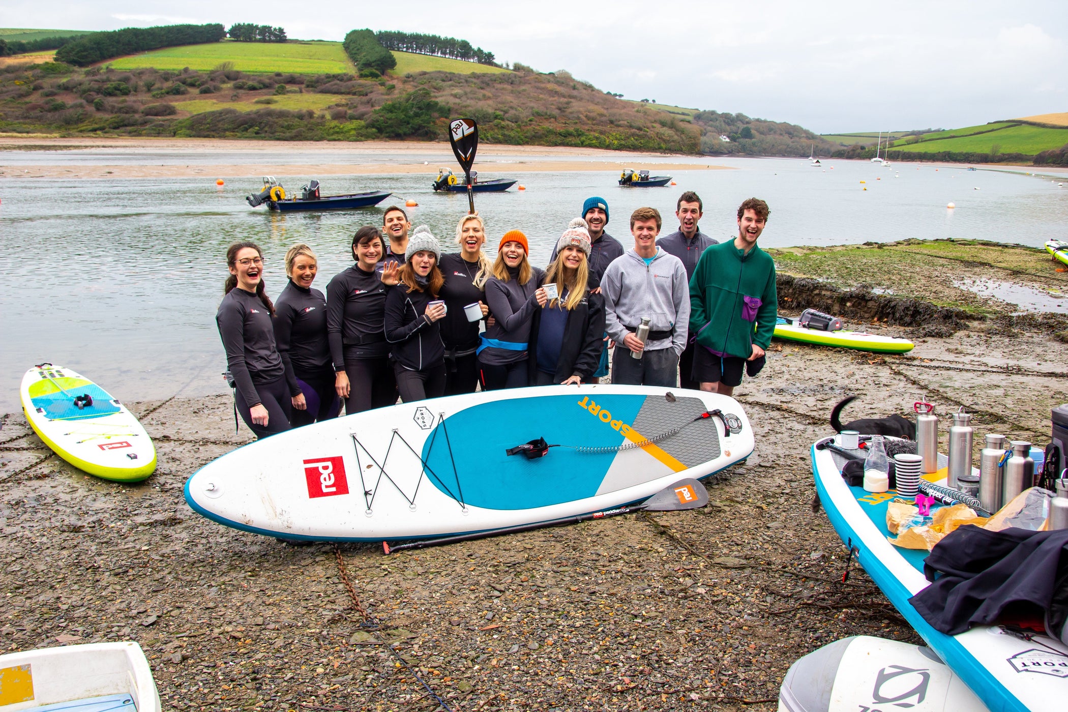 group stood by river next to red original paddle board