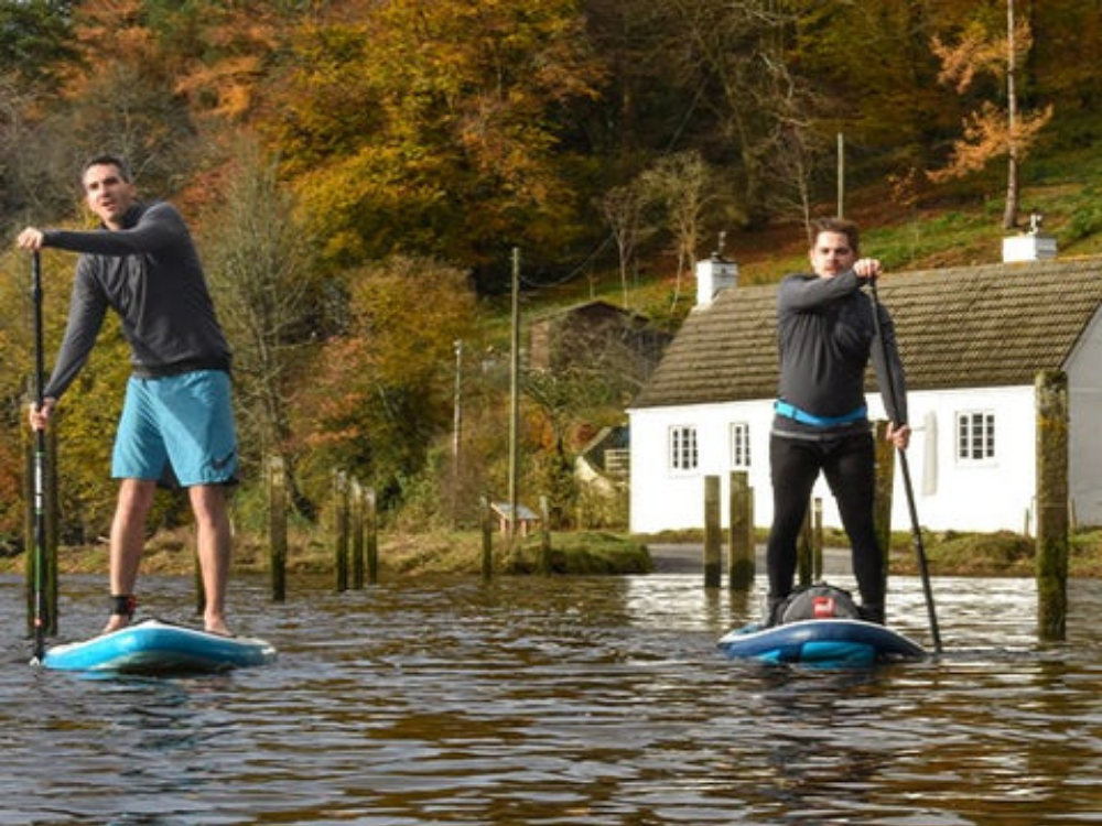 two men paddle boarding on river