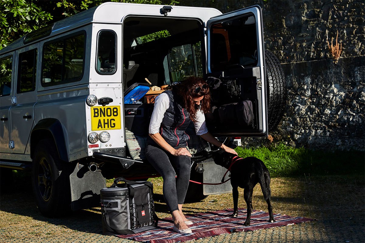 Woman Sitting At The Back Of Her Car With Her Dog