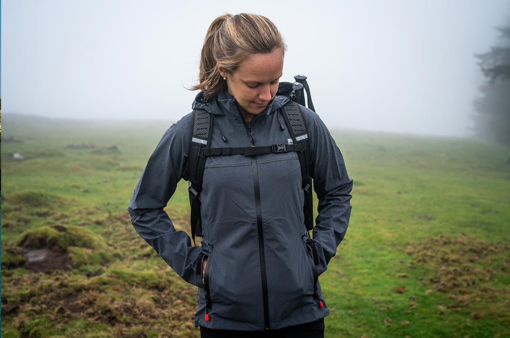 Woman wearing a waterproof active jacket and carrying a 30L Backpack standing in a field