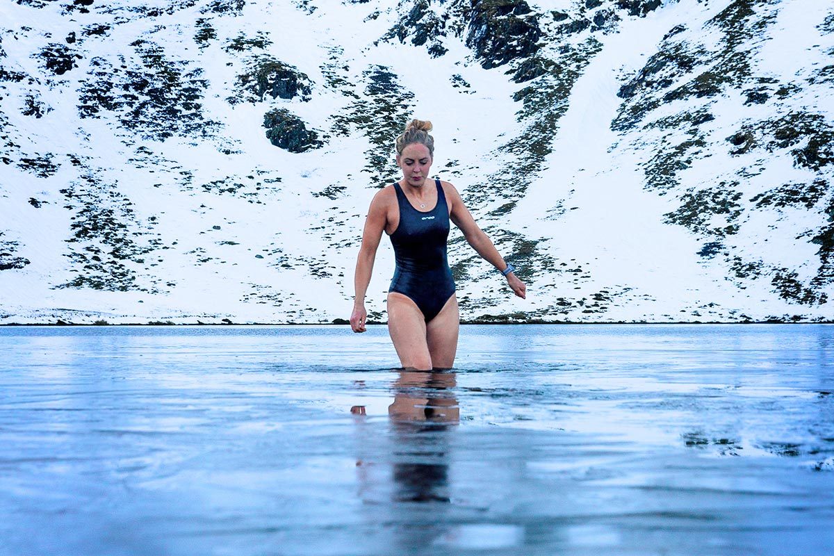 Woman walking into an icy lake on a snowy day