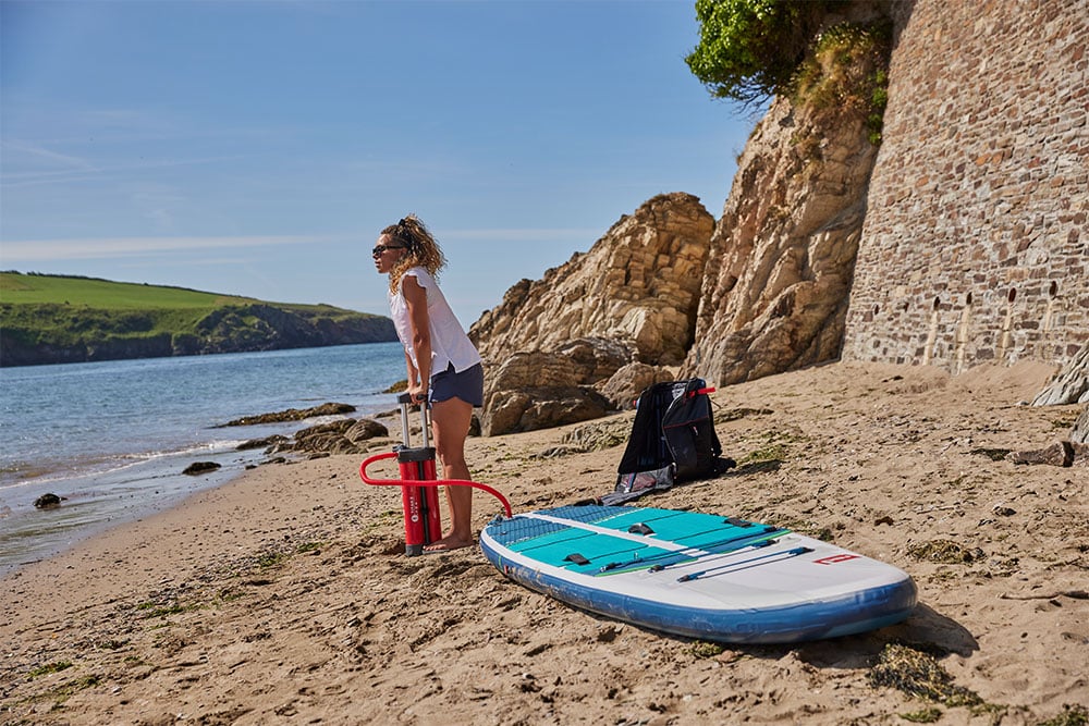 Woman inflating Red MSL paddle board on the beach