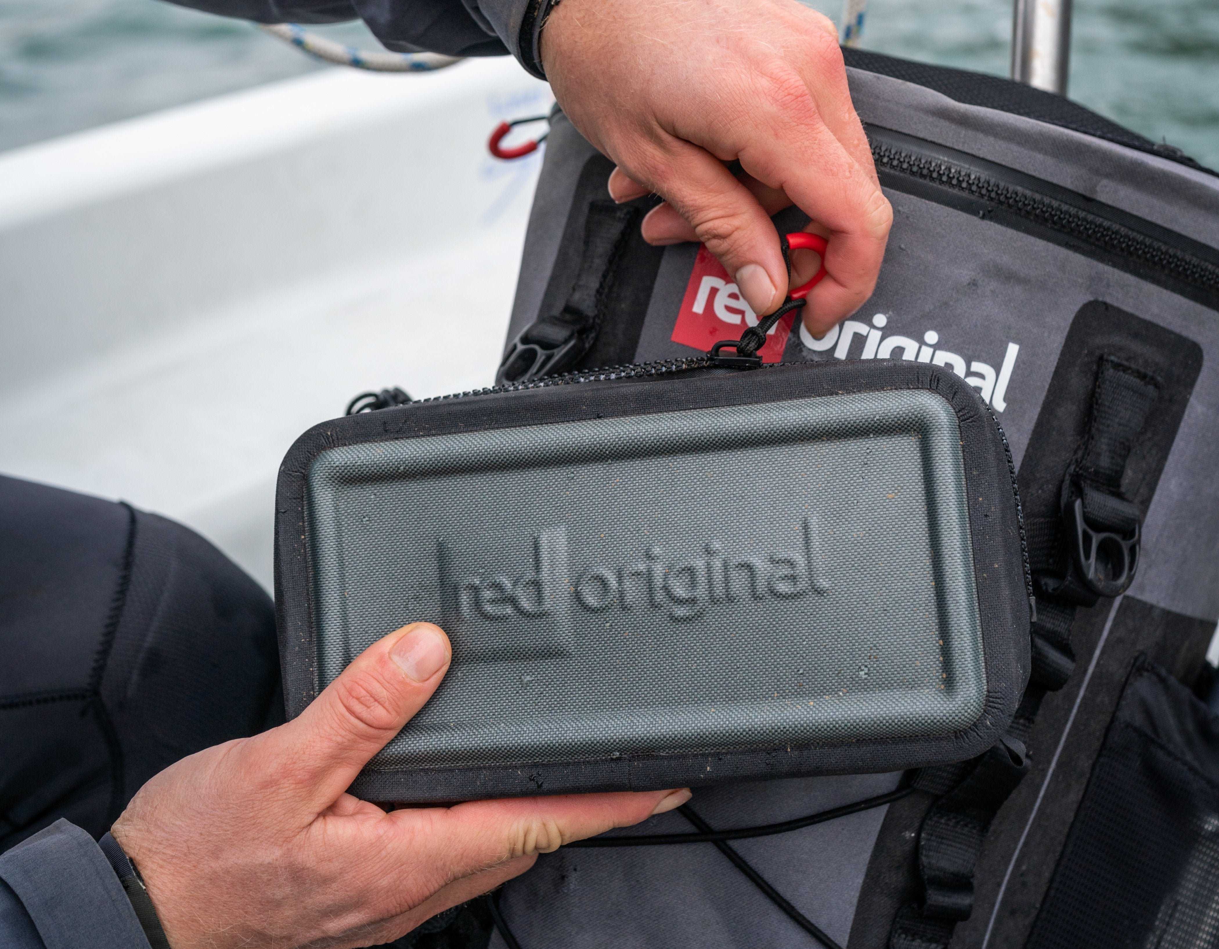 Close up of a Red Dry Pouch in front of a Deck Bag. 